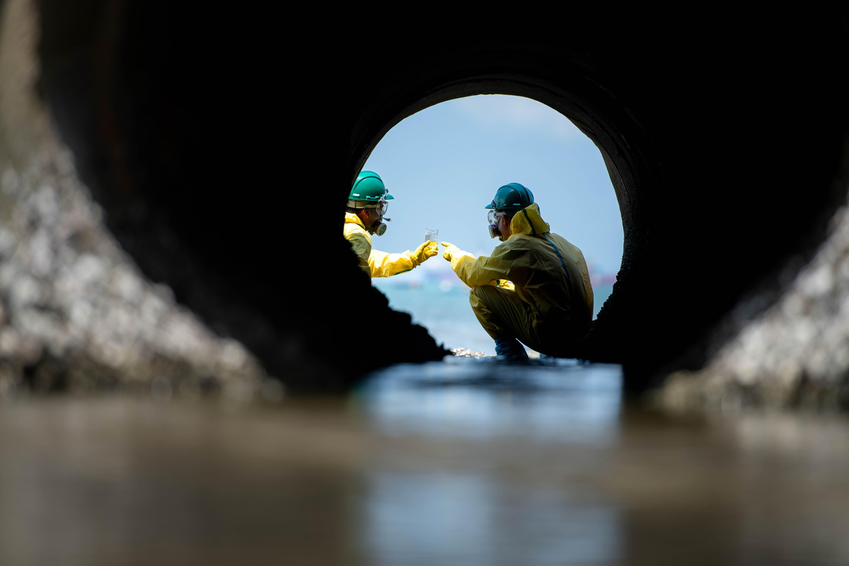 Ein Umweltteam in Schutzanzügen entnimmt Abwasserproben